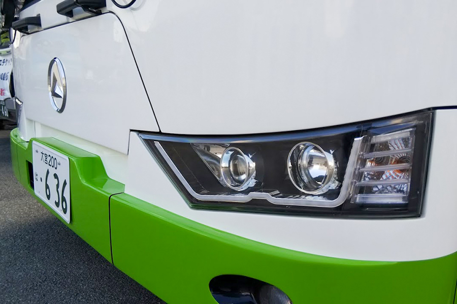 山梨県甲府市の山梨交通本社でデモンストレーション中のBEVバス、アルファバスe-City L10のフロントフェイス。鋭いデザインのヘッドライトが日本車とかなり印象が違う。