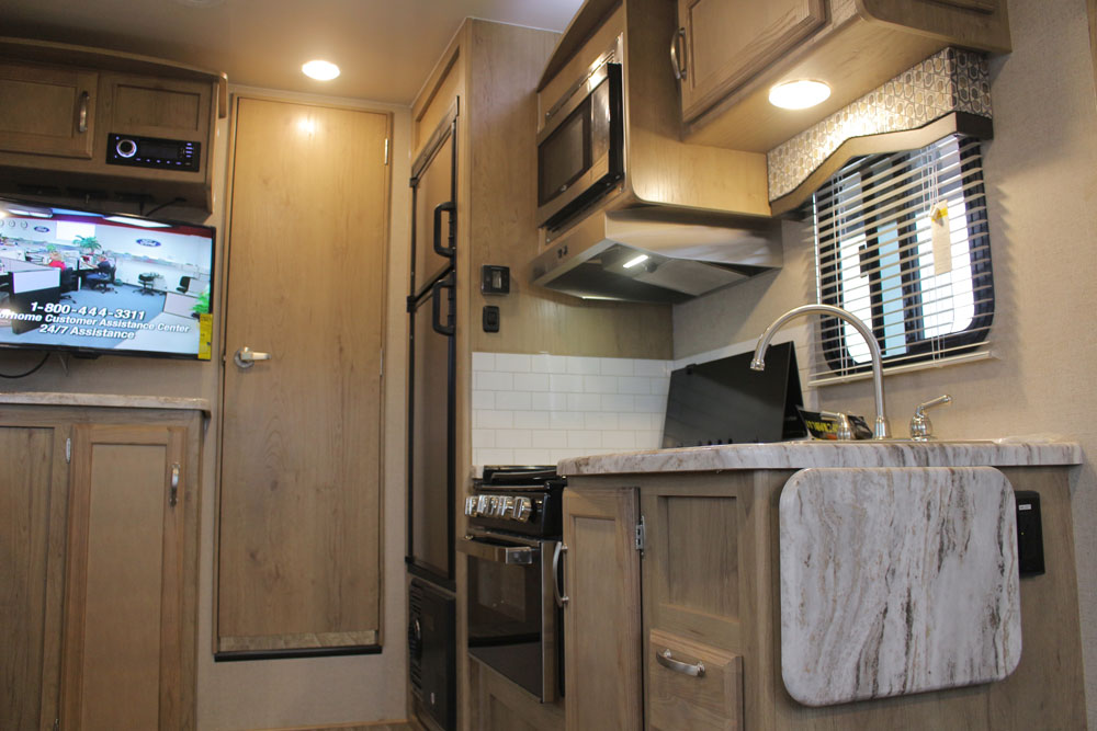 ステンレスシンク、ガスレンジ、電子レンジ、2ドア冷蔵庫、ガス・電気温水器を備えるキッチン。