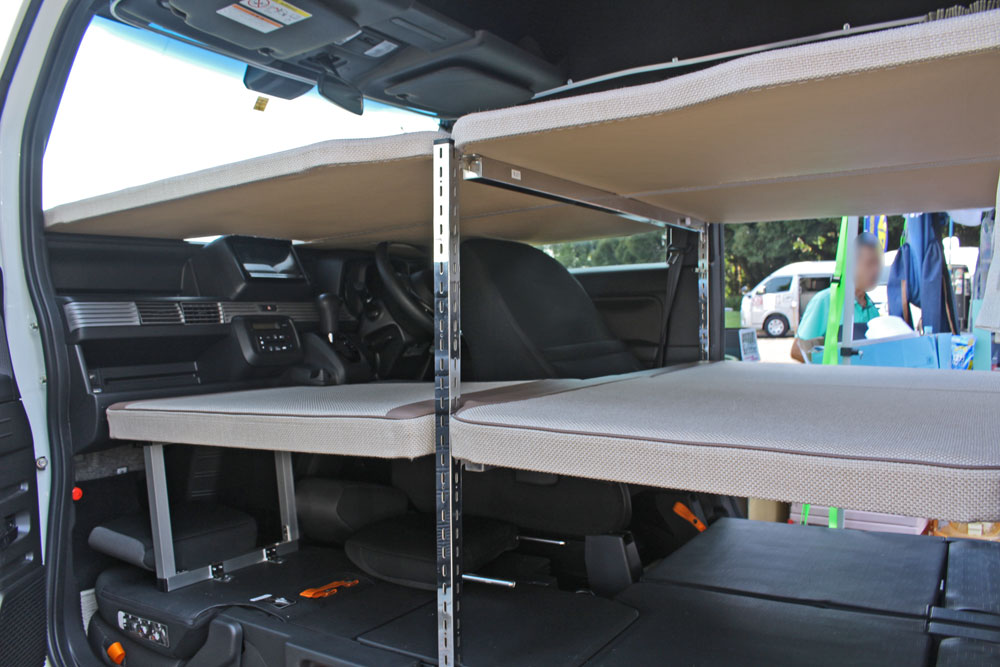 独自のベッドフレーム機構は、柱に無数の穴があいており、好みの高さにバーを渡せば、軽量ベッドマットを載せるだけでセッティングできる。車内の前端まで、ベッドのためのスペースとして使っているのがよく分かる。