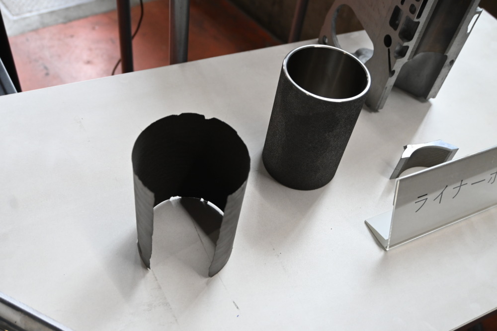右が従来エンジンに使われている鋳鉄製のシリンダーライナー。左がSUSミラーボアコーティングのステンレスの層。非常に薄くなっていることがわかる。